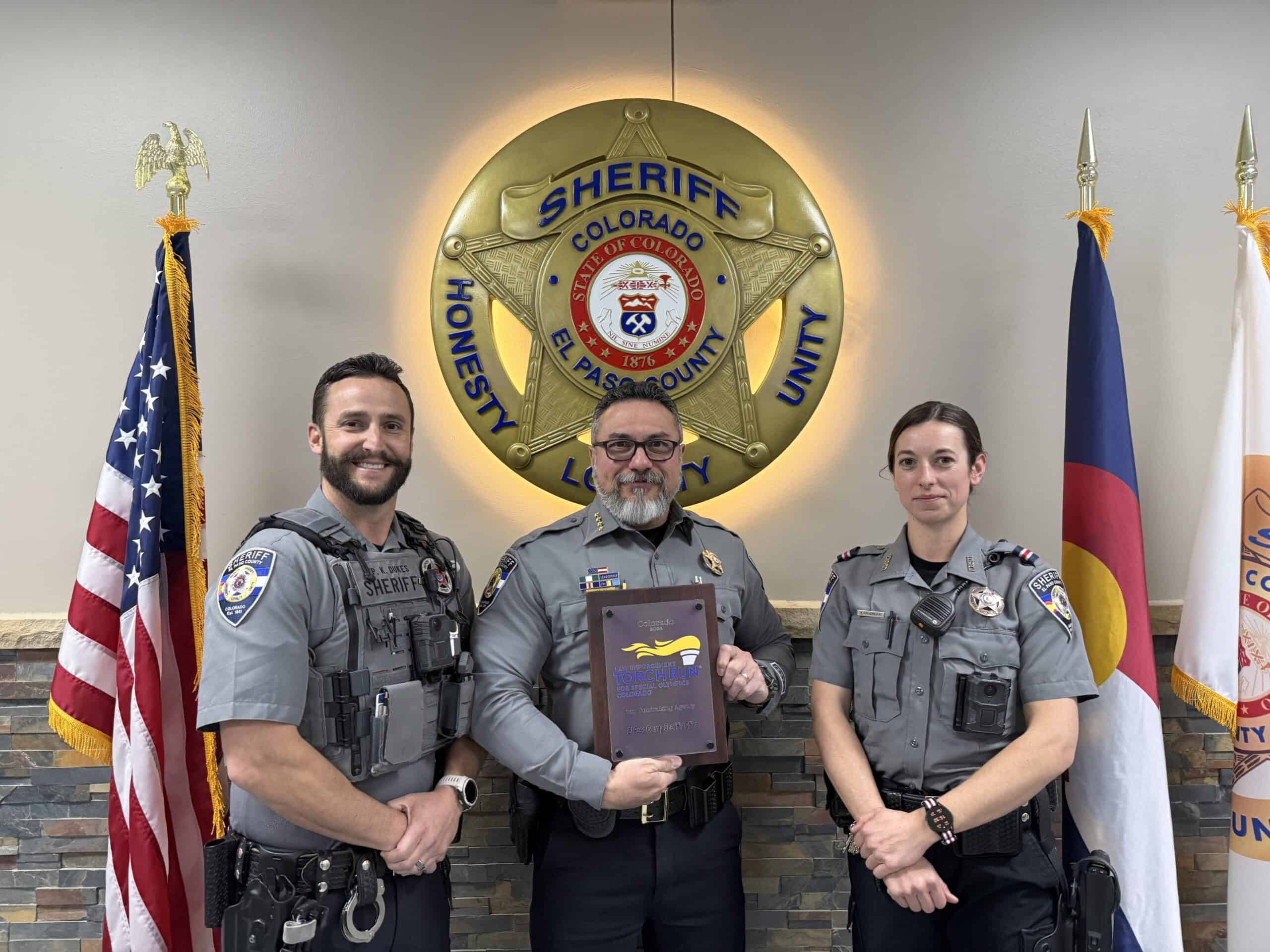 Deputies and Sheriff hold the award plaque from Special Olympics, Colorado.